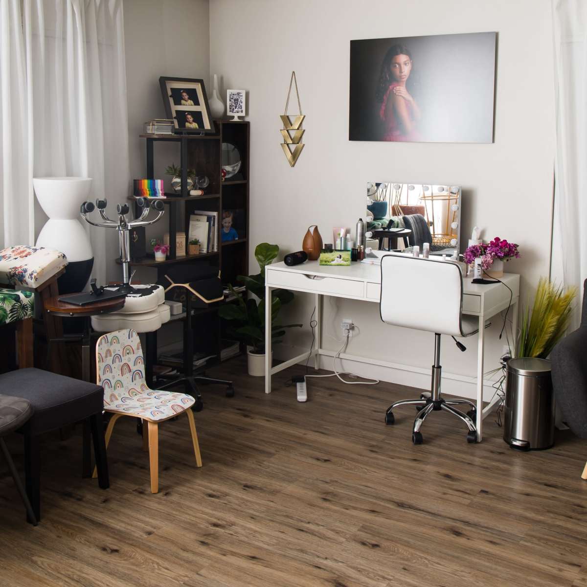 A modern room with a variety of furniture including a desk with a mirror, a chair, and an area for a child, along with decorative items and plants.