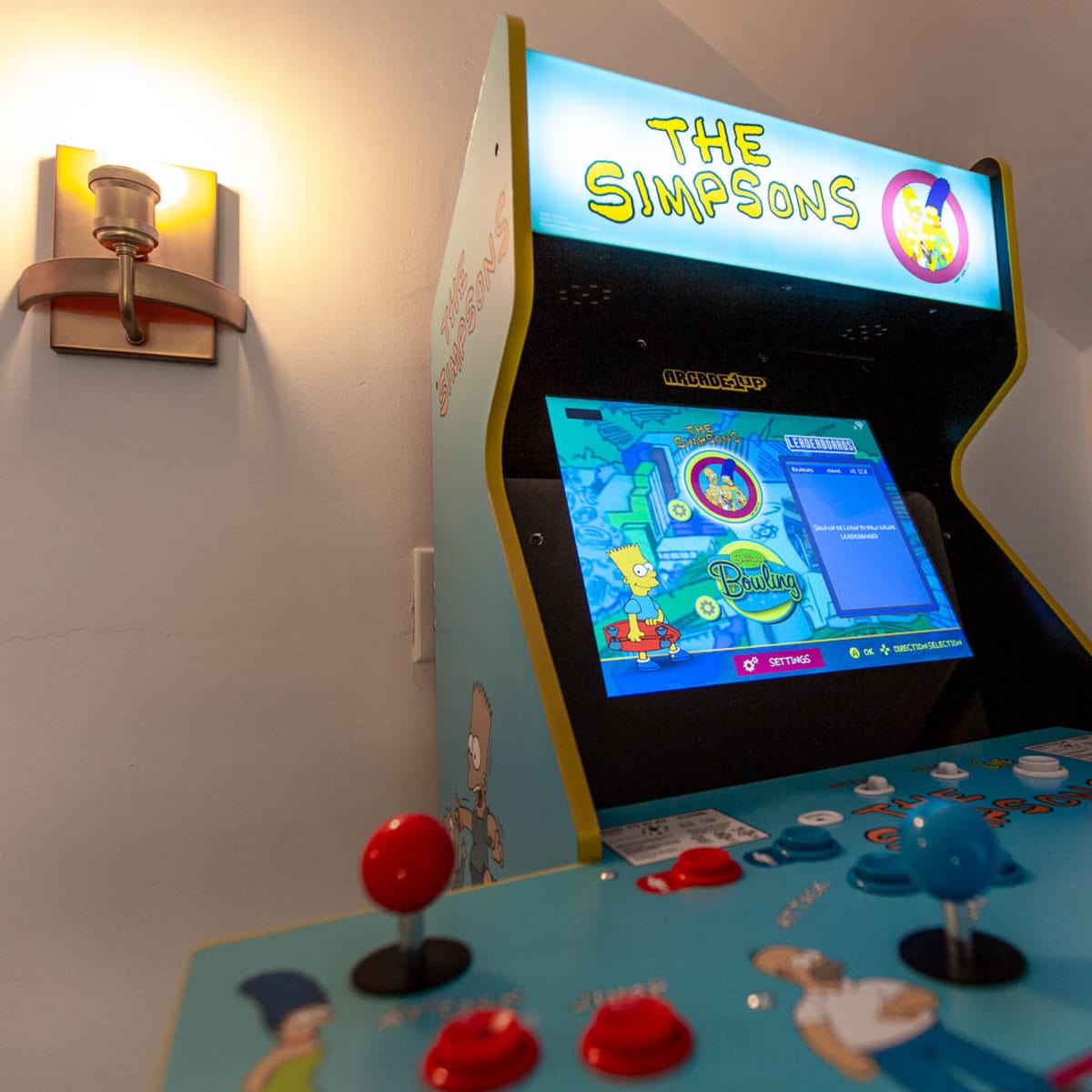A retro arcade cabinet featuring "The Simpsons" video game, with colorful buttons and a vibrant display.