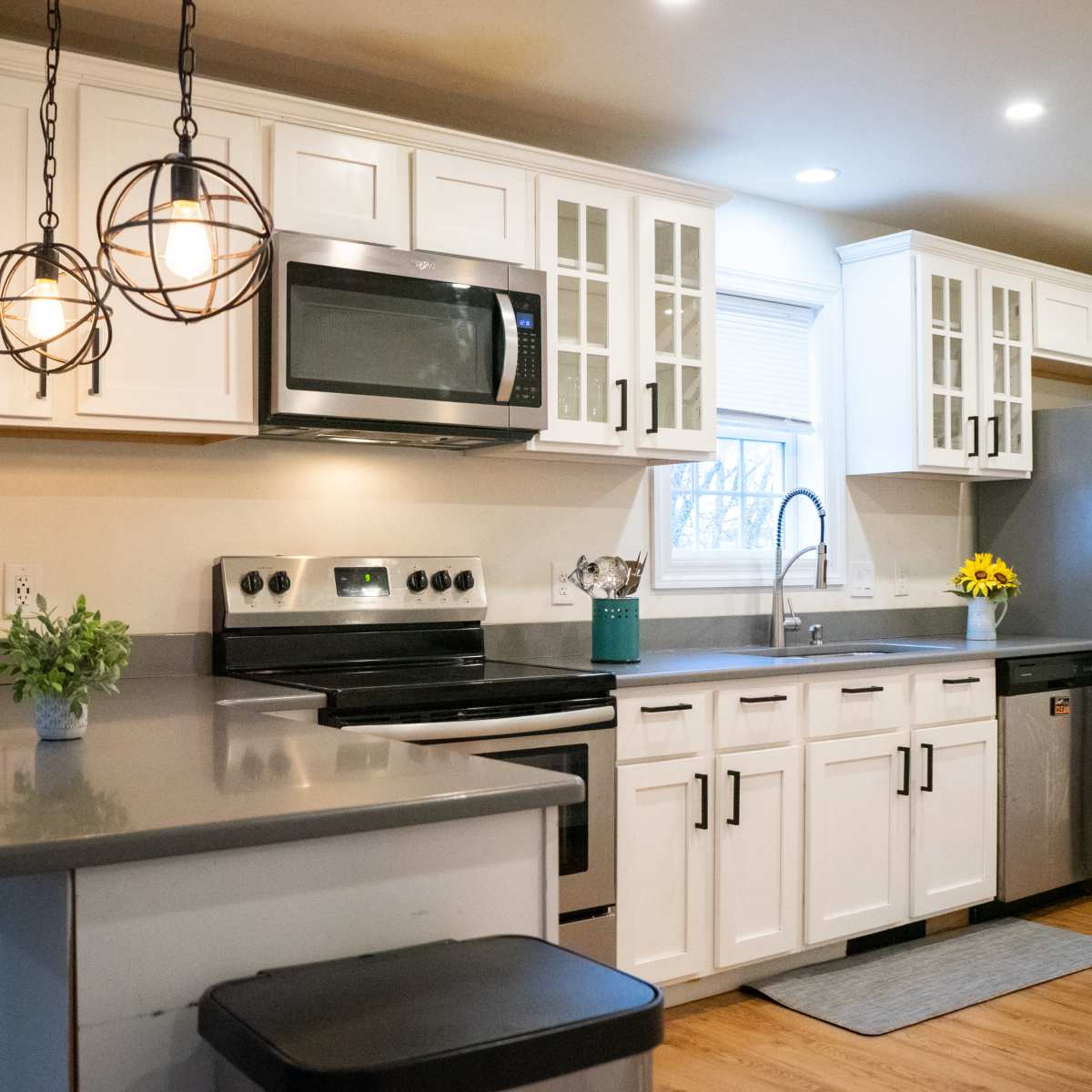 A modern kitchen featuring white cabinets, stainless steel appliances, and a gray countertop.