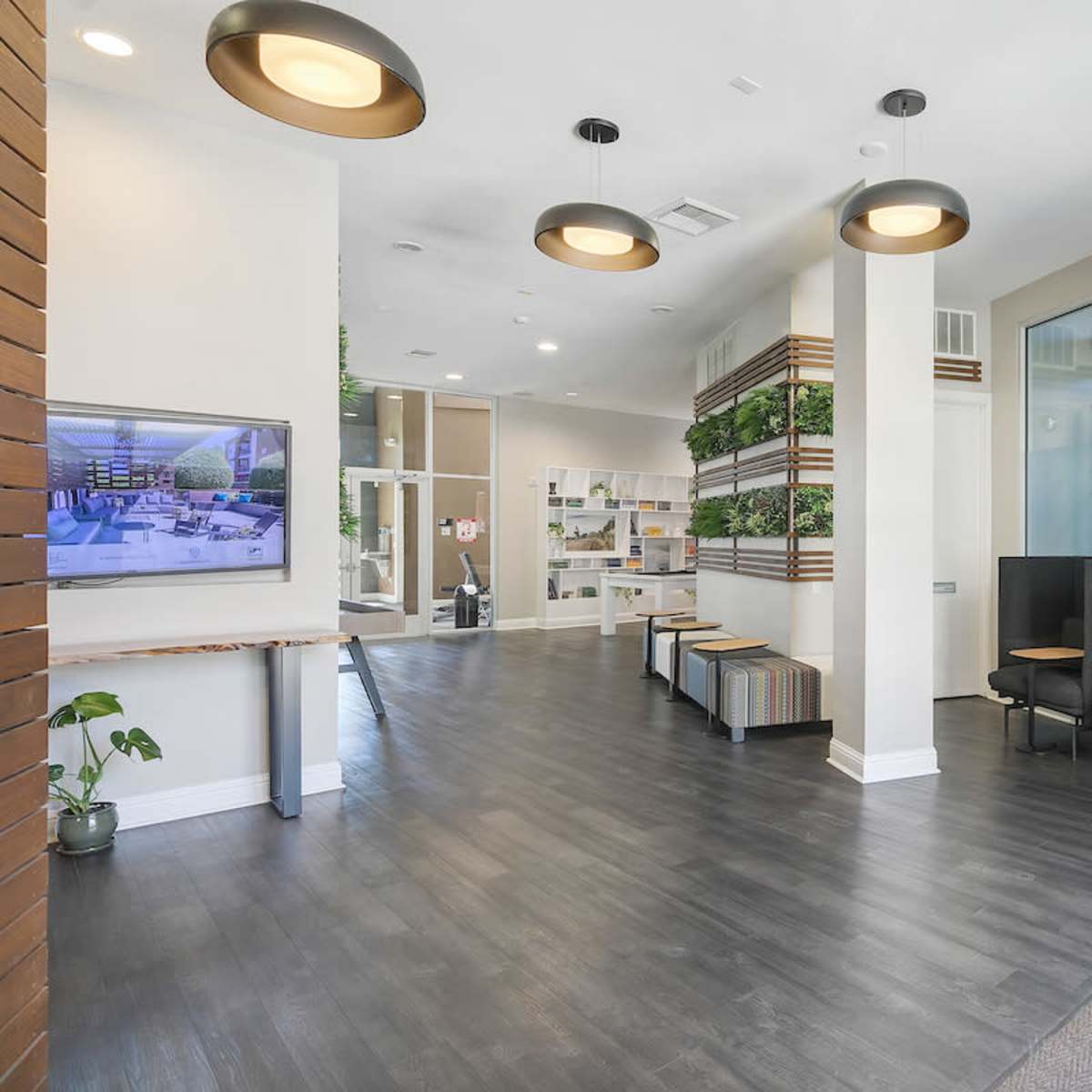 A modern reception area with seating, greenery, and a digital screen displaying images on one wall.