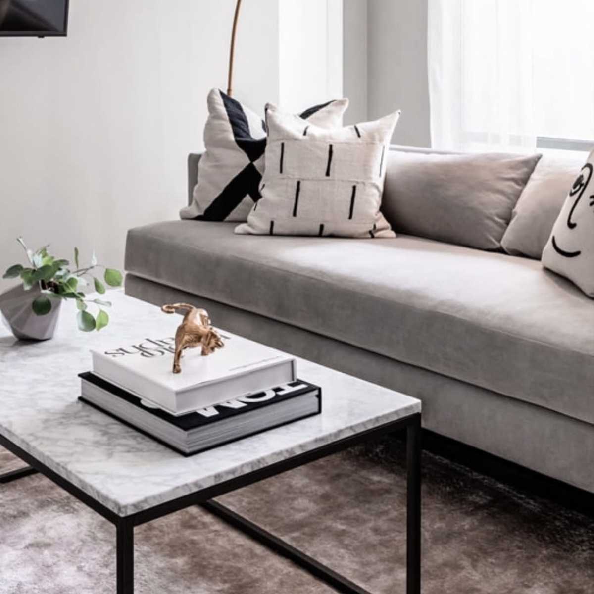 The living room features a light gray sofa with patterned cushions, a marble coffee table, and a modern arc floor lamp.