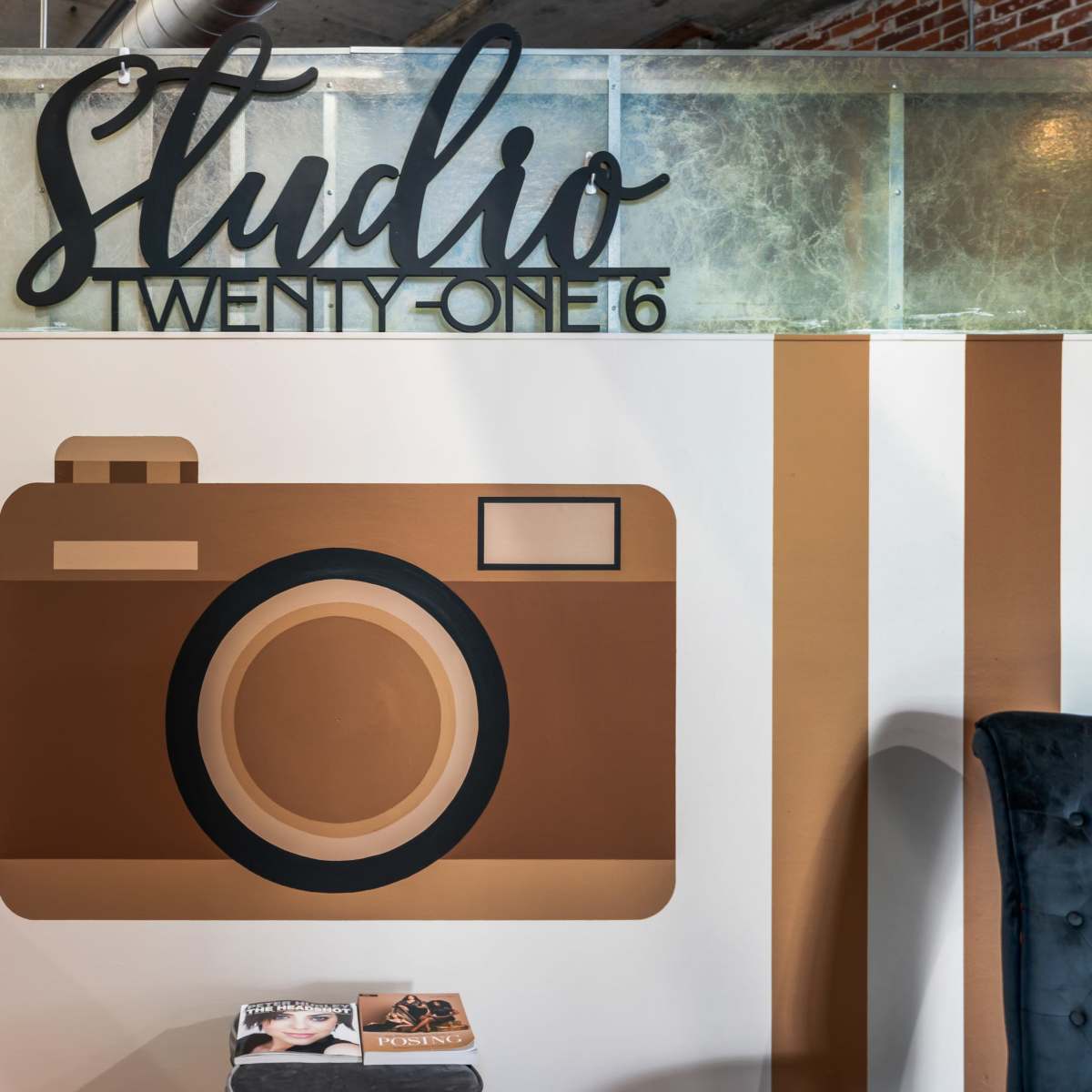 A wall featuring the text "Studio Twenty-One 16" above a large illustration of a camera, flanked by decorative stripes in brown and cream colors.