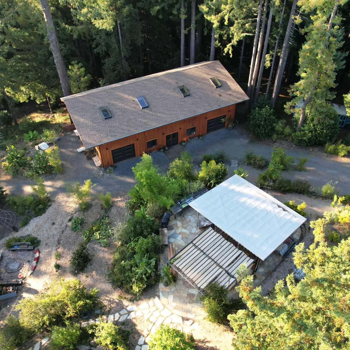 An aerial view shows a large wooden building and a covered patio surrounded by greenery and trees.