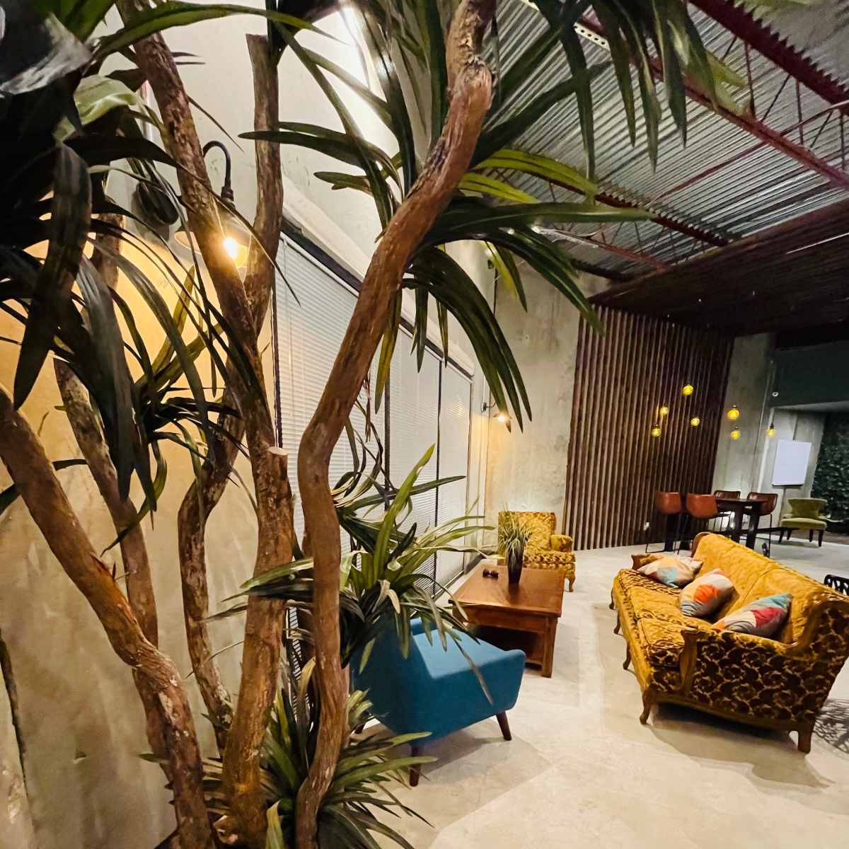 A cozy interior space featuring a brown sofa, a blue chair, a wooden coffee table, and decorative plants.