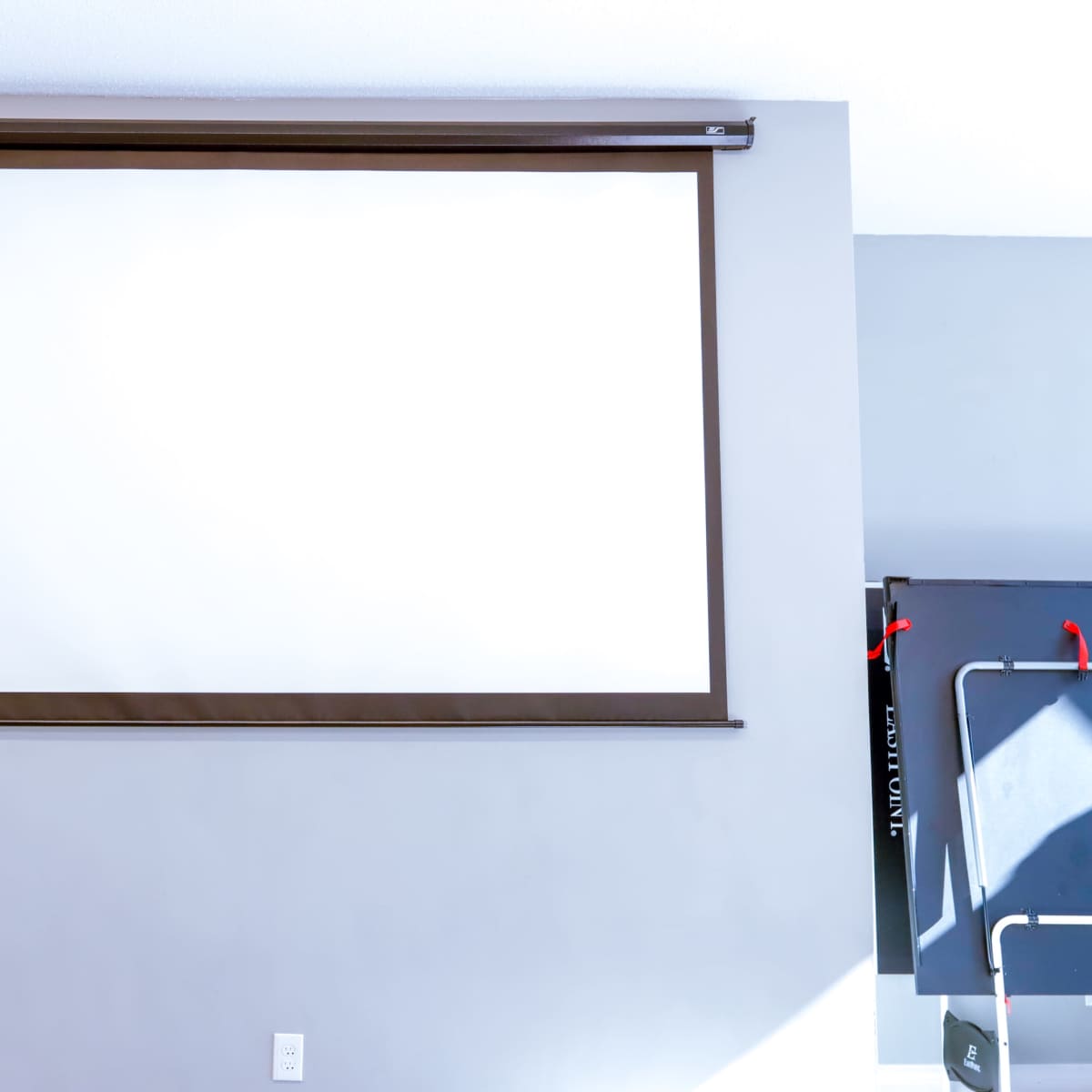 A large retractable projection screen is mounted on a light gray wall.