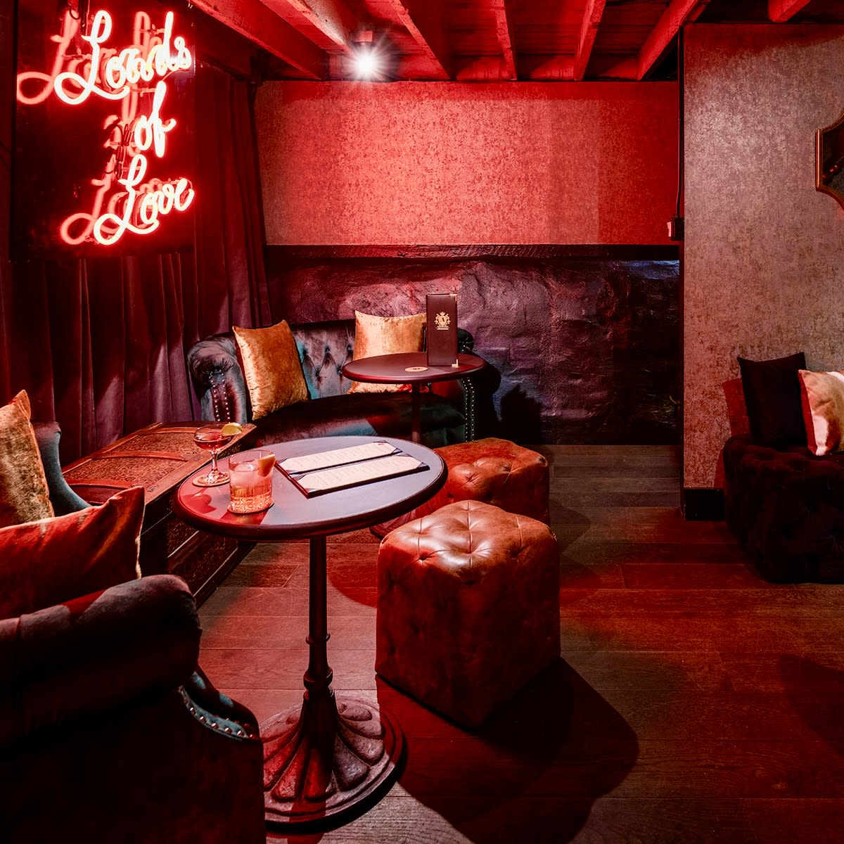 A dimly lit lounge with plush seating and a neon sign that reads "Hobbs of Love."