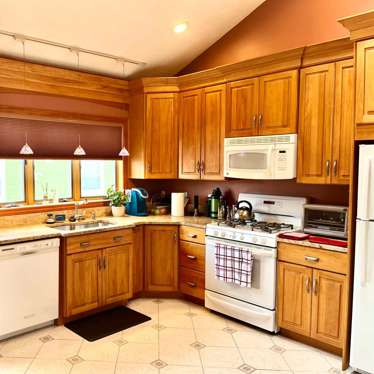 A well-organized kitchen with wooden cabinets, a white stove, and a countertop featuring a small plant and kitchen appliances.