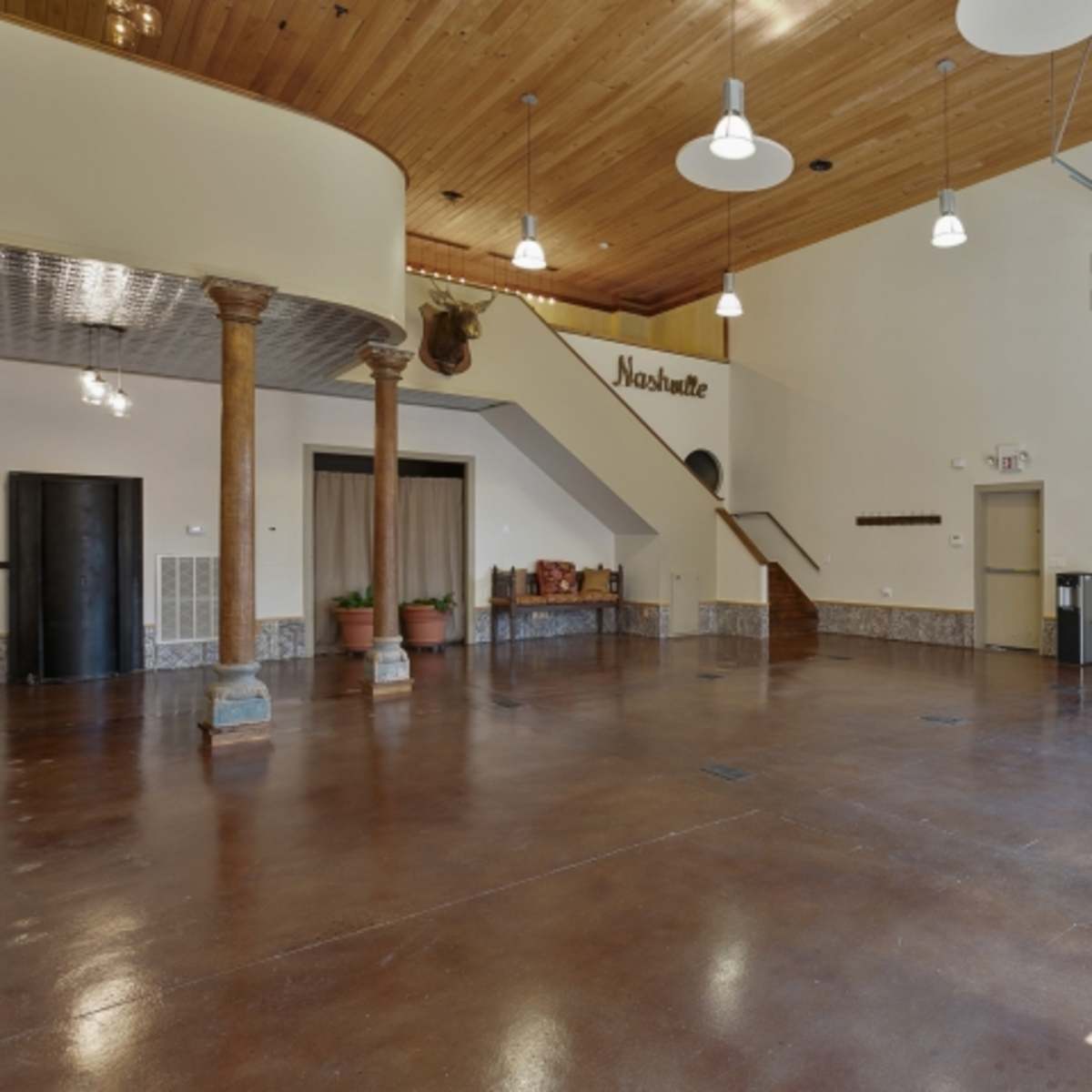 An open interior space featuring a polished concrete floor, wooden ceiling, and a large garage door.