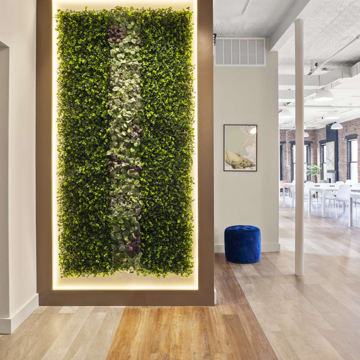 A vertical green wall featuring various plants, illuminated by spotlights, within a modern interior space.