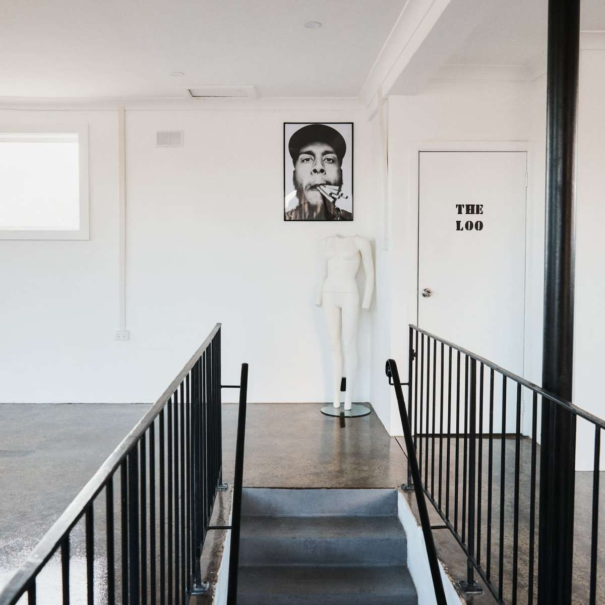 A staircase leading to a room with a large portrait on the wall and a mannequin positioned nearby, with a door labeled "THE LOO" visible.