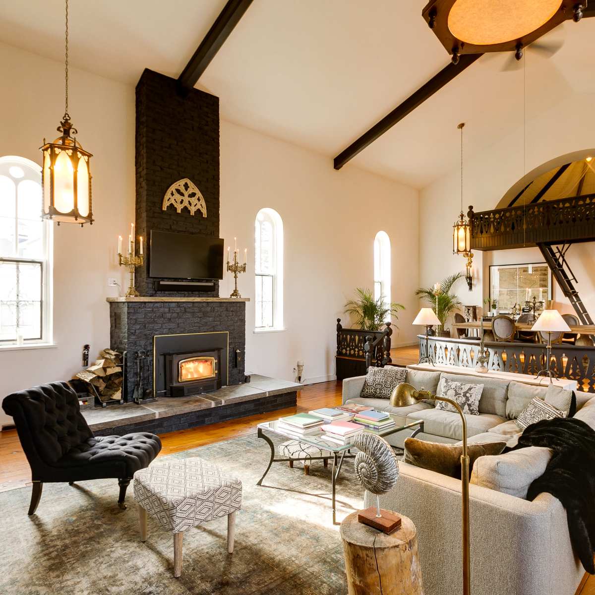 A spacious living room with a central fireplace, high ceilings, and a mix of comfortable seating arrangements.