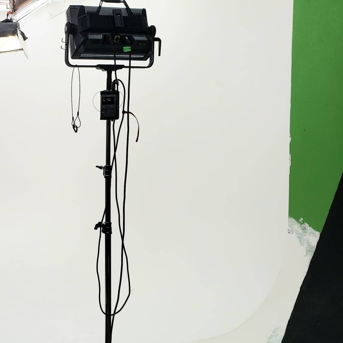 A photography studio with a seamless white backdrop, a lighting setup, and a tripod for equipment.