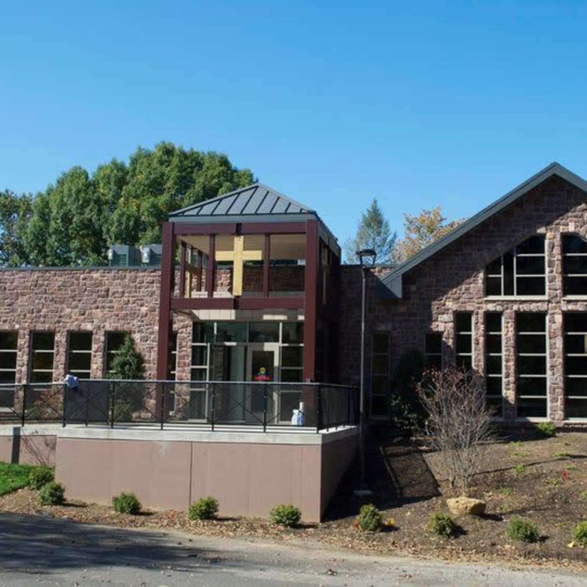 A modern stone building with large windows and a distinctive entrance featuring a glass and metal structure.