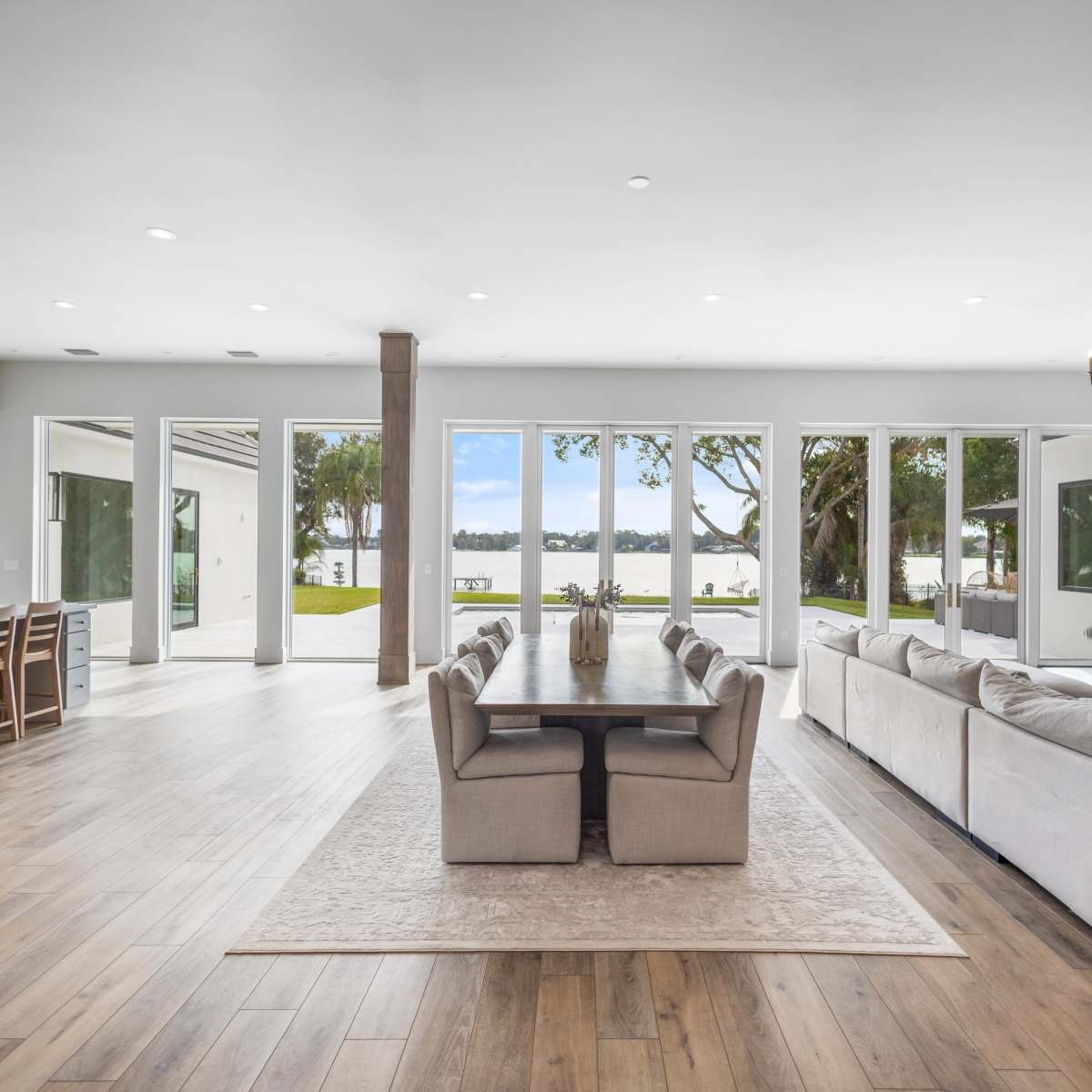 A spacious, elegantly designed living area that opens to a view of the outdoors, featuring a dining table, comfortable seating, and large windows.
