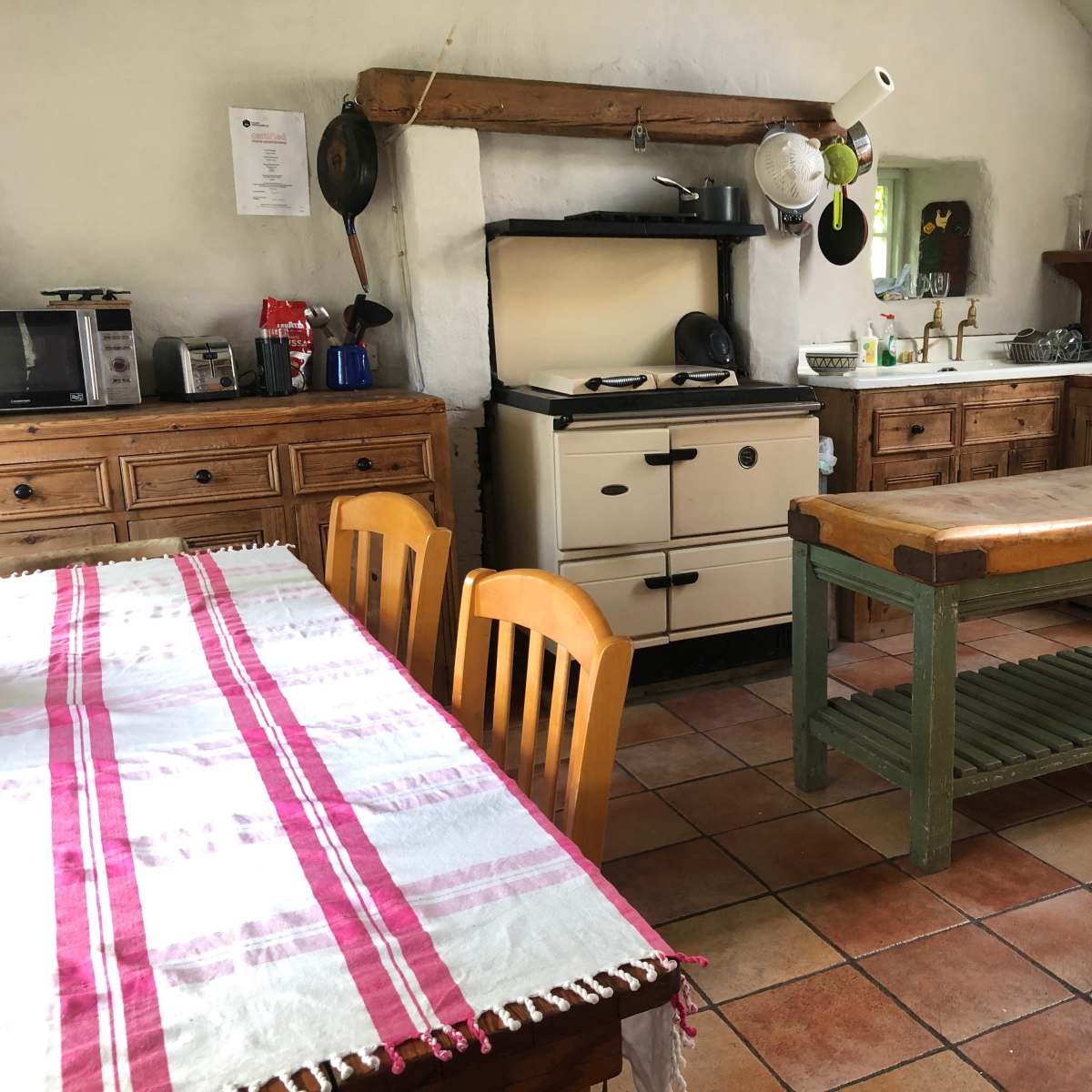 A rustic kitchen with wooden cabinets, a stove, and a dining table set with a checkered cloth.