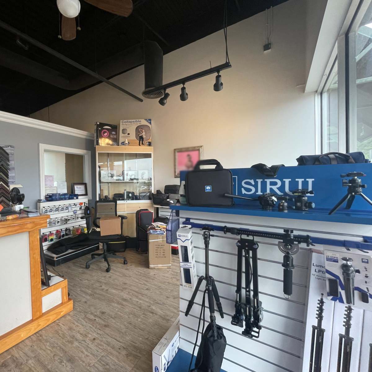 A photography and framing store interior with display shelves, framing samples, and tripods.