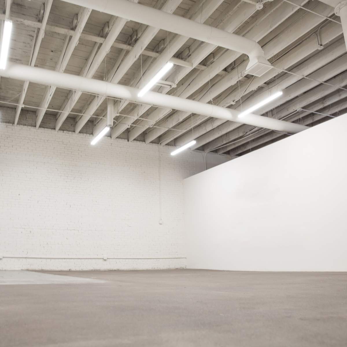 An empty, well-lit room with white brick walls and a concrete floor.