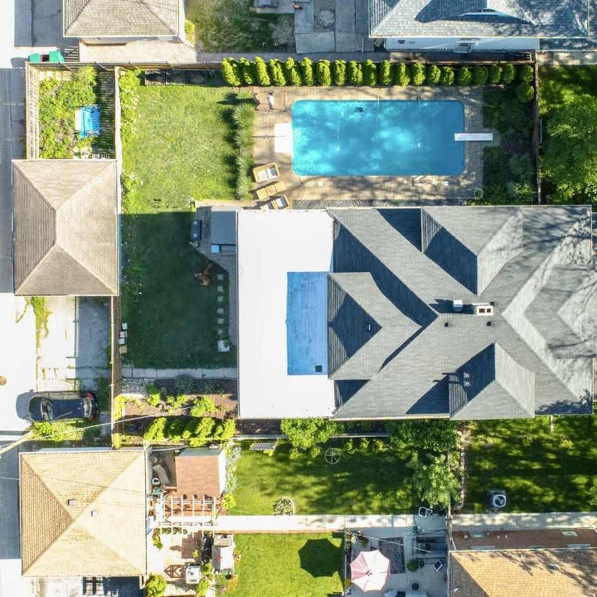 An aerial view of residential houses with a swimming pool and green lawns in a suburban area.