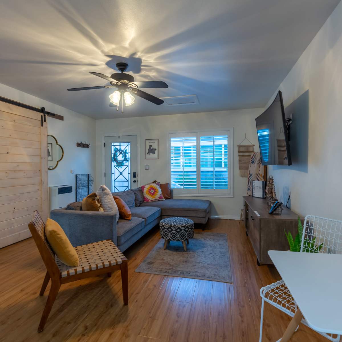 A modern living room with a sectional sofa, a sliding barn door, and a wall-mounted television.