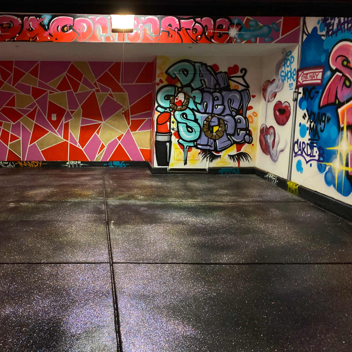 A brightly painted room with colorful graffiti covering the walls and a shiny black floor.