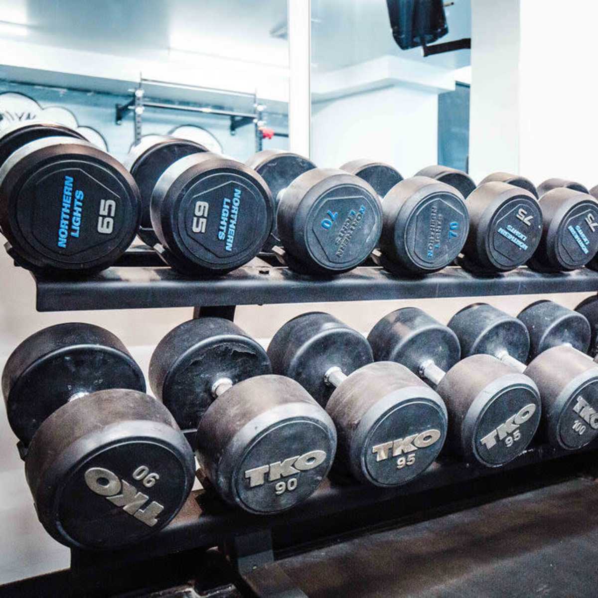A rack displays various sizes of dumbbells in a gym setting.