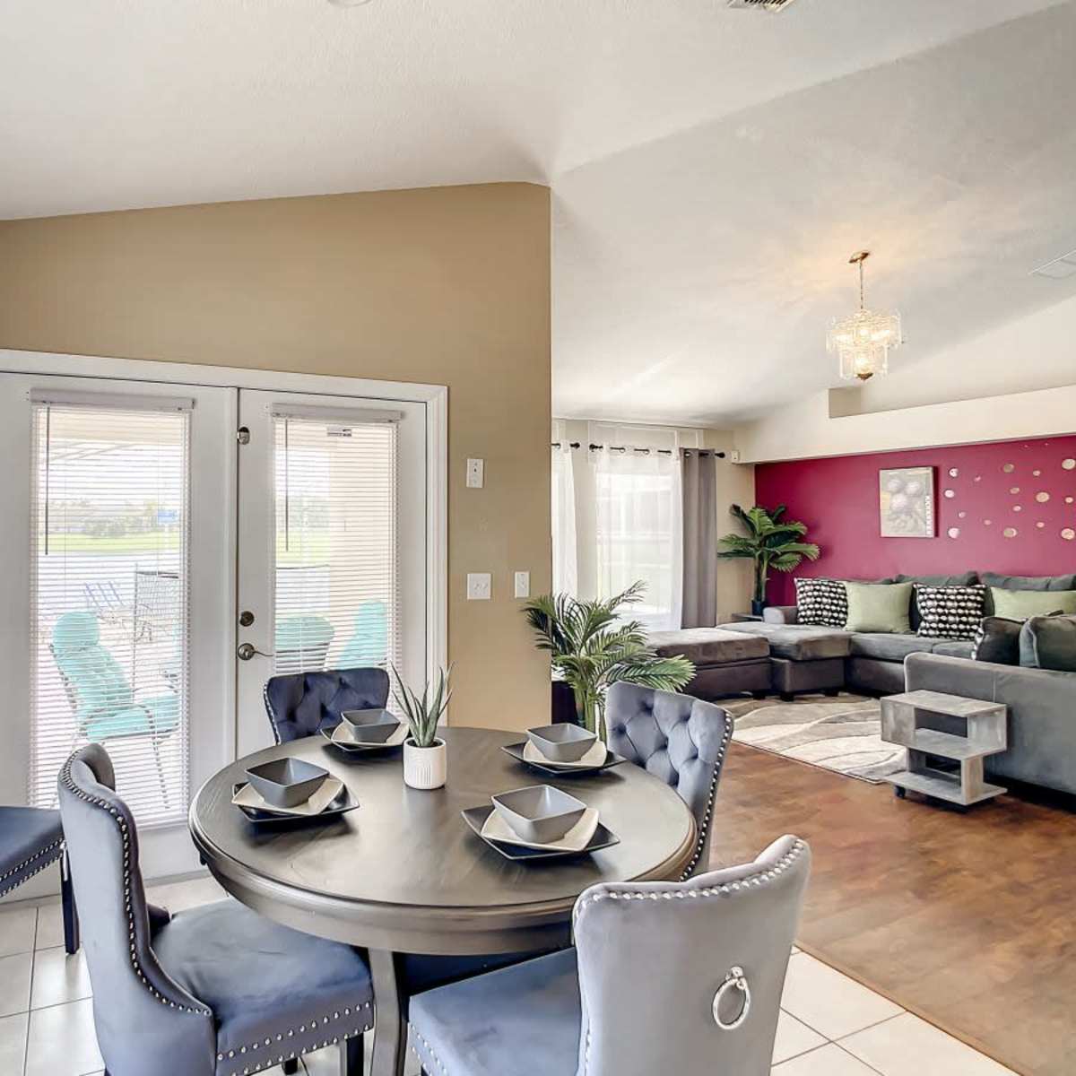 A dining area features a round table with four upholstered chairs, complemented by a sliding glass door leading to an outdoor space.
