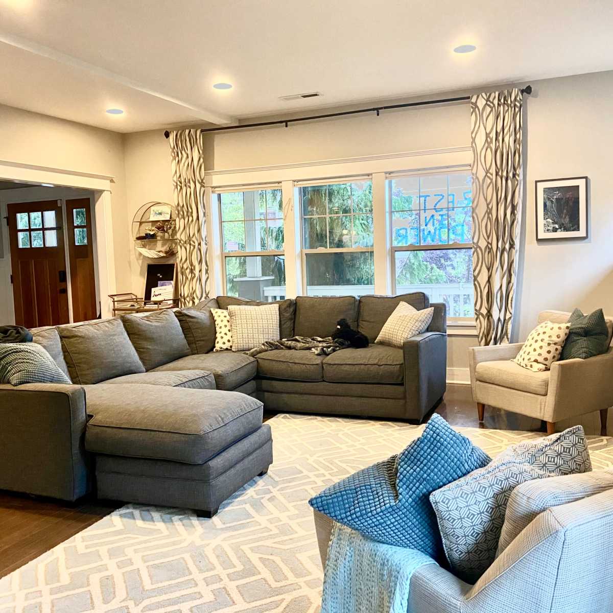 A spacious living room with a large sectional sofa, an armchair, and a decorative fireplace, all arranged around a geometric area rug.