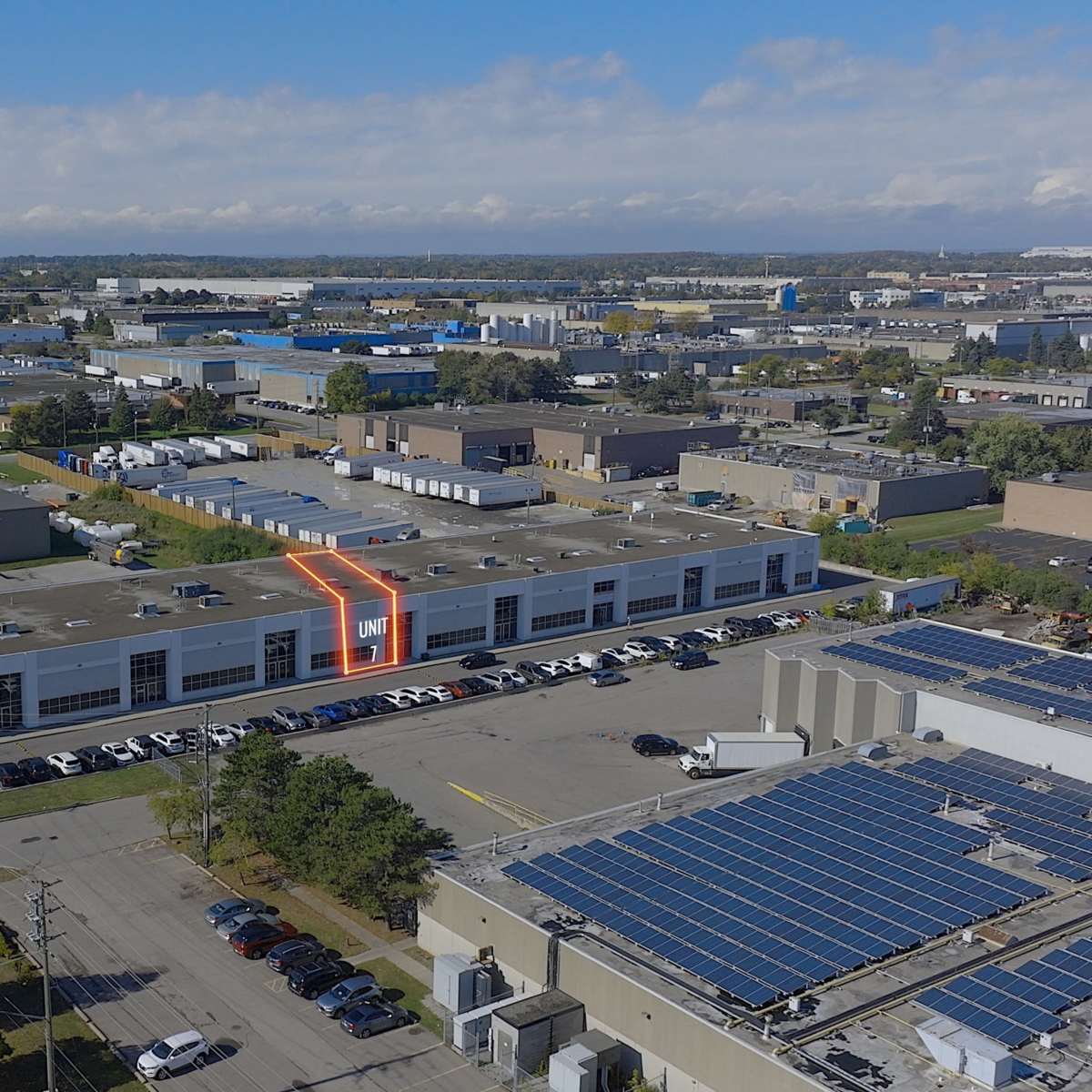 An aerial view of a commercial building with a highlighted unit, surrounded by various warehouses and industrial facilities in an urban area.