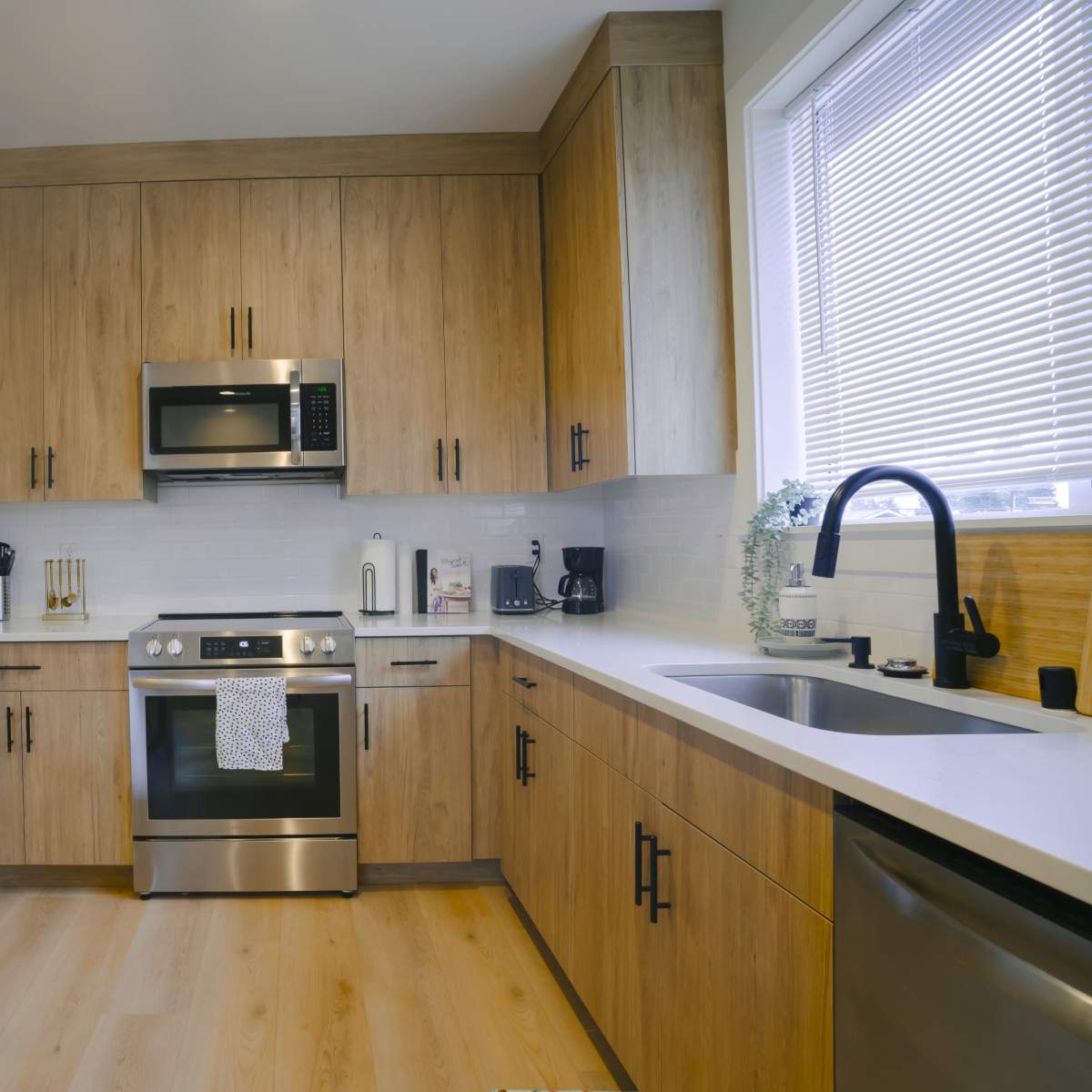 A modern kitchen features wooden cabinetry, stainless steel appliances, and a dining table.