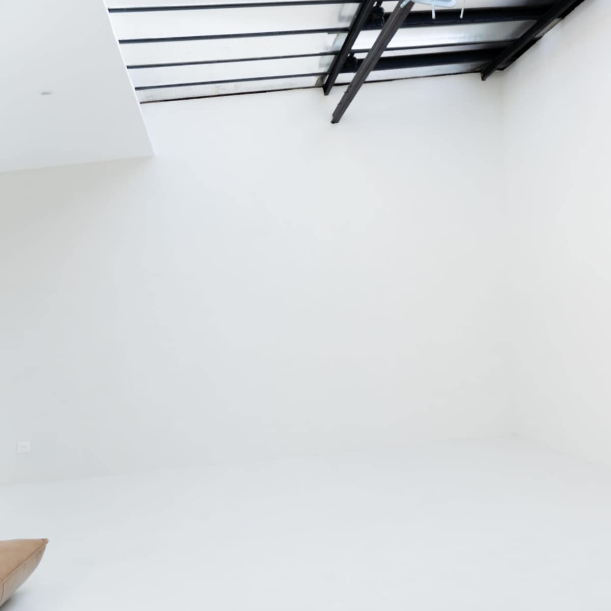 A large, empty room with white walls and a skylight.
