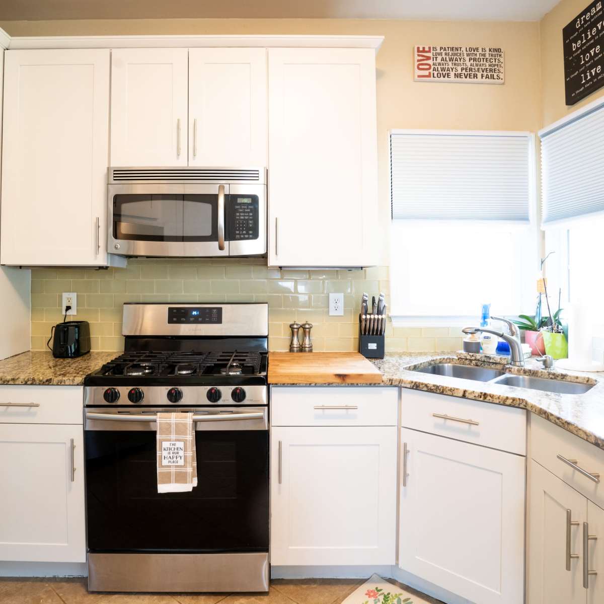 A modern kitchen with white cabinetry, a stainless steel oven, and a granite countertop.