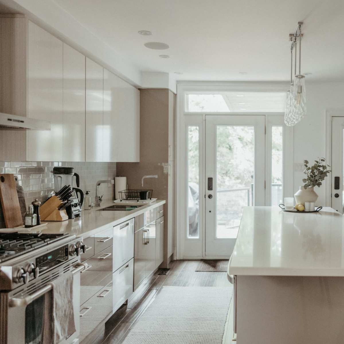 A modern kitchen features sleek cabinetry, a large island with seating, and doors leading to an outdoor space.