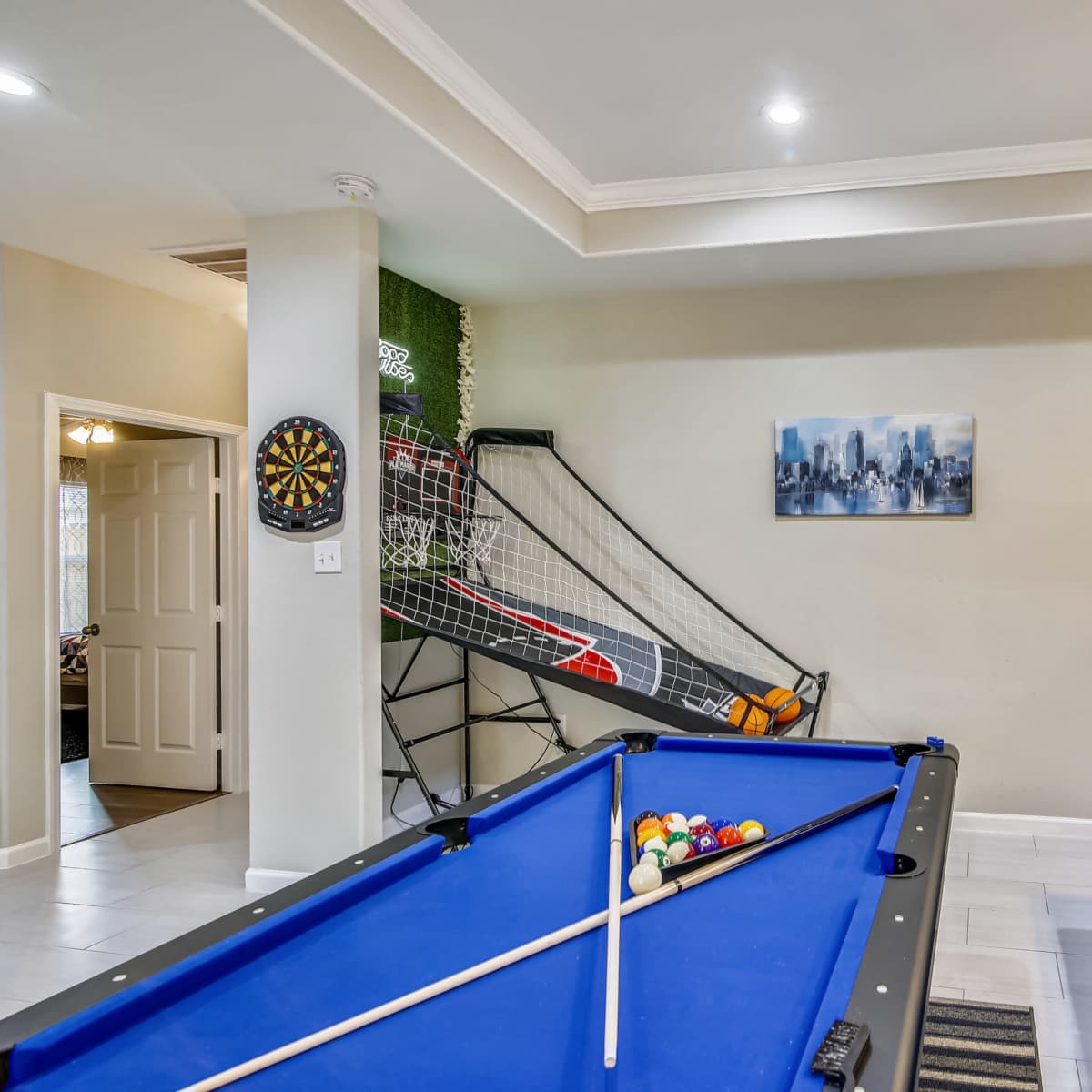 A game room featuring a blue pool table, a dartboard on the wall, and a soccer goal net in the background.
