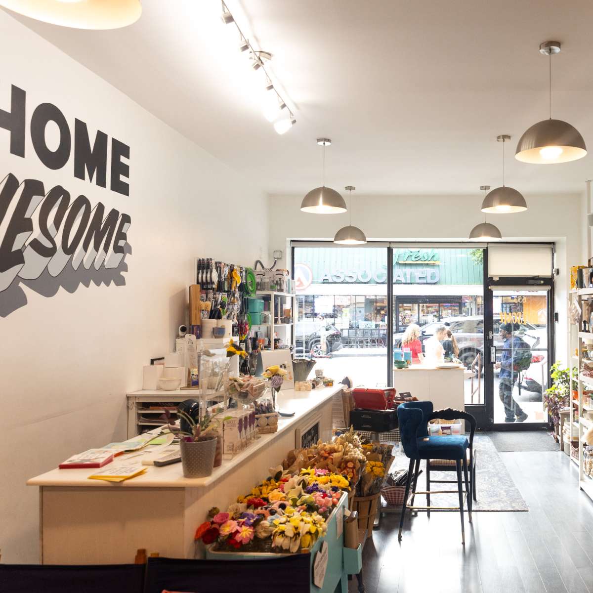 A retail store features shelves filled with various merchandise, a checkout counter, and a large window displaying an outdoor street scene.