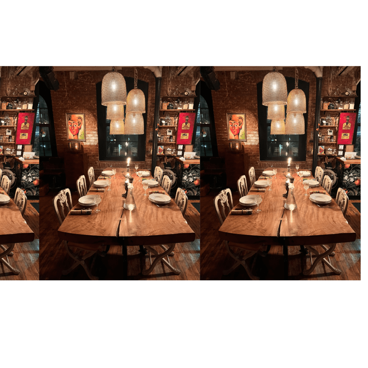 A long wooden dining table is set with plates and candles under hanging pendant lights in a cozy, warmly lit room decorated with artwork.