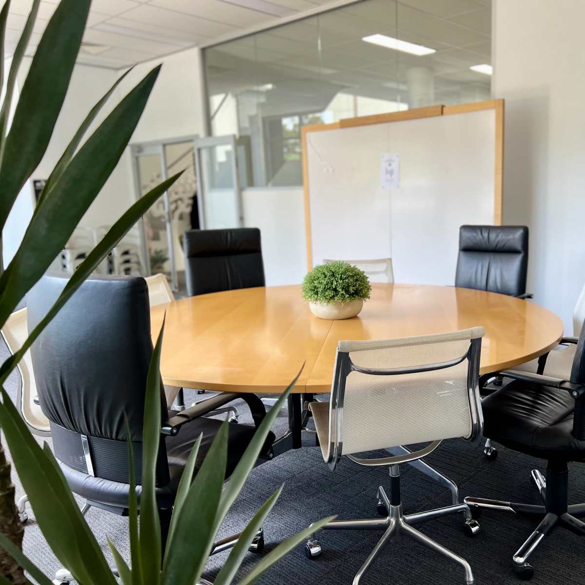 A round wooden conference table surrounded by six chairs in a modern meeting room.
