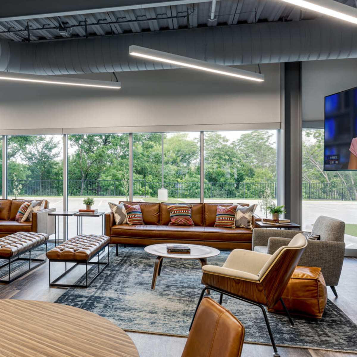 A modern lounge area with large windows, stylish sofas, and a mix of seating arrangements.