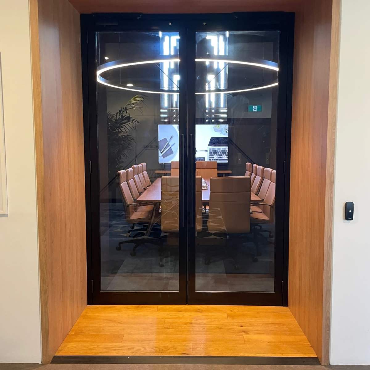 A glass door opening to a modern conference room with a long table and several chairs.