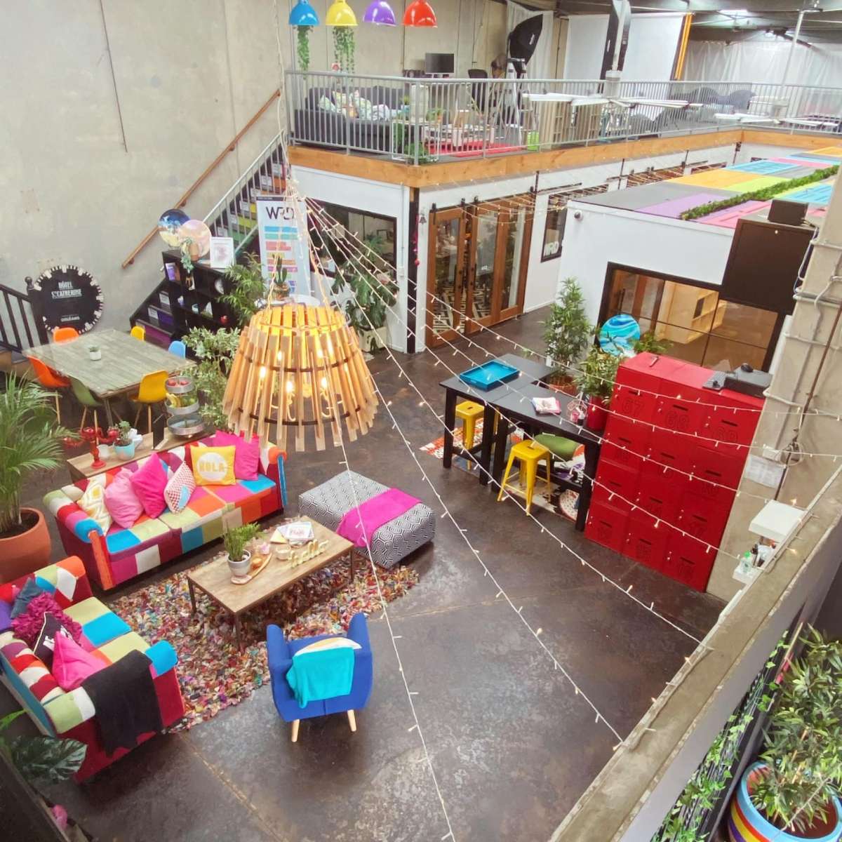 A colorful, multi-functional indoor space featuring various seating areas, plants, and vibrant decor elements.