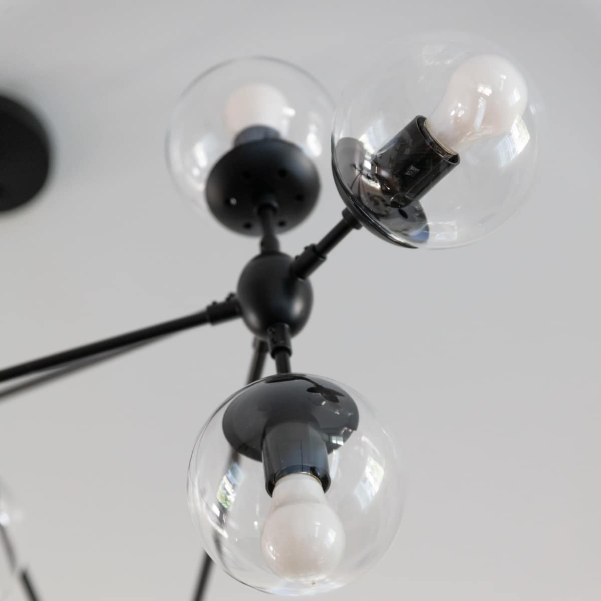 A modern ceiling light fixture with multiple spherical glass bulbs connected by black metal arms.