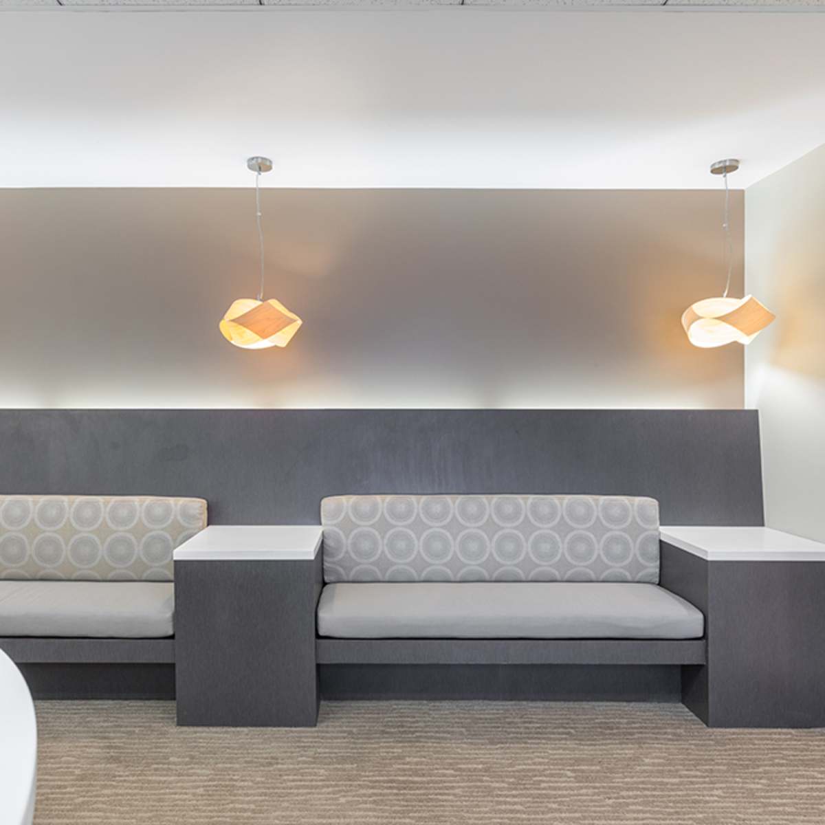 A minimalist lounge area with two gray couches and modern pendant lights hanging from the ceiling.