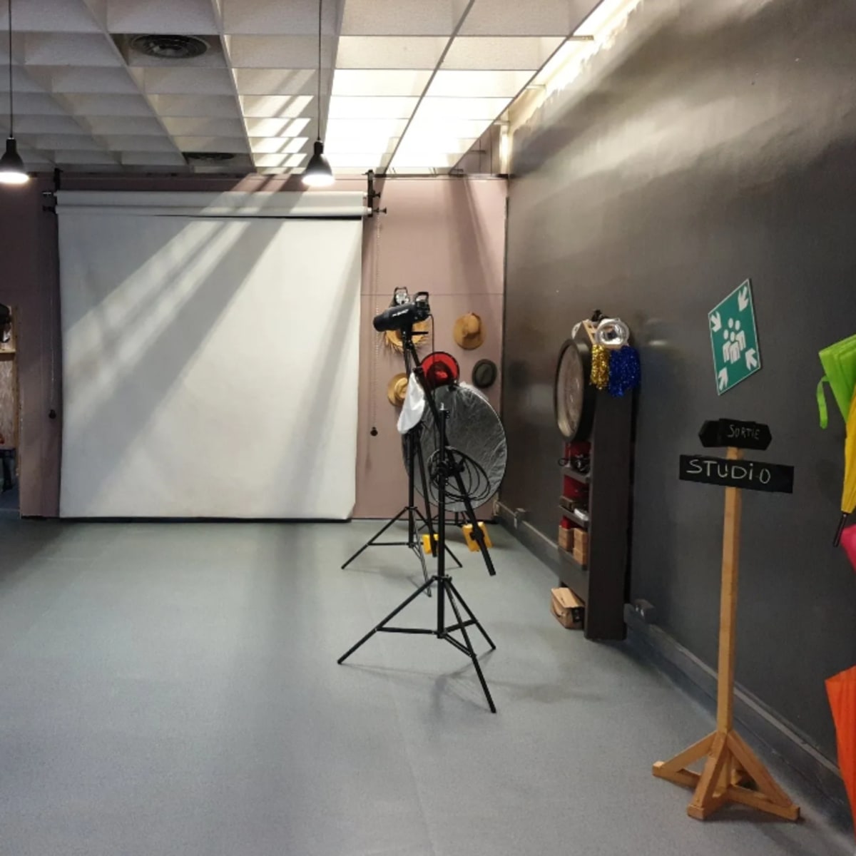 A photography studio with a backdrop, lighting equipment, and a chalkboard sign labeled "STUDIO."