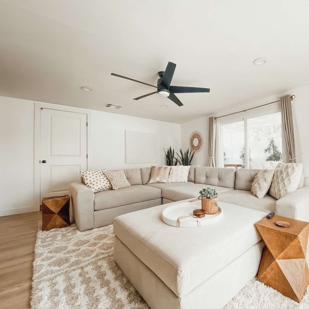 A spacious living room featuring a large sectional sofa, a round coffee table, and a light-colored rug.