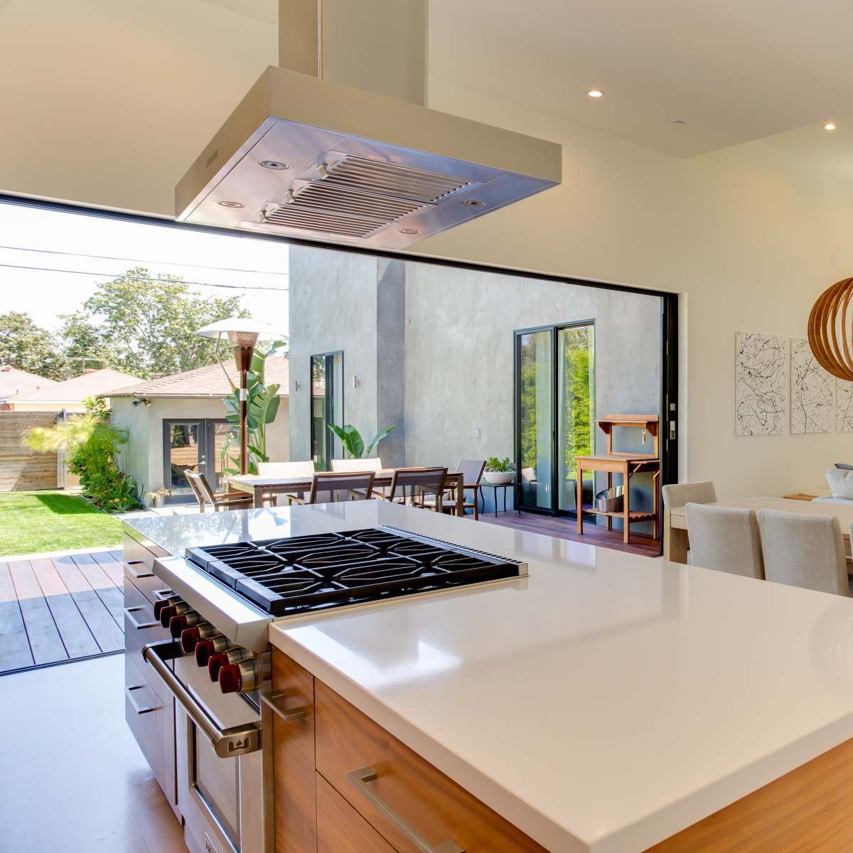 The open-concept kitchen features a sleek island with a gas stove, seamlessly connecting to a dining area and living space with large windows that invite natural light.