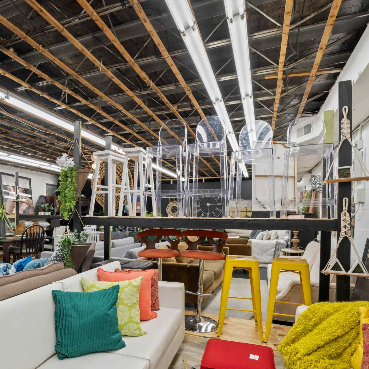 A furniture showroom featuring various seating options, decorative items, and an exposed ceiling.
