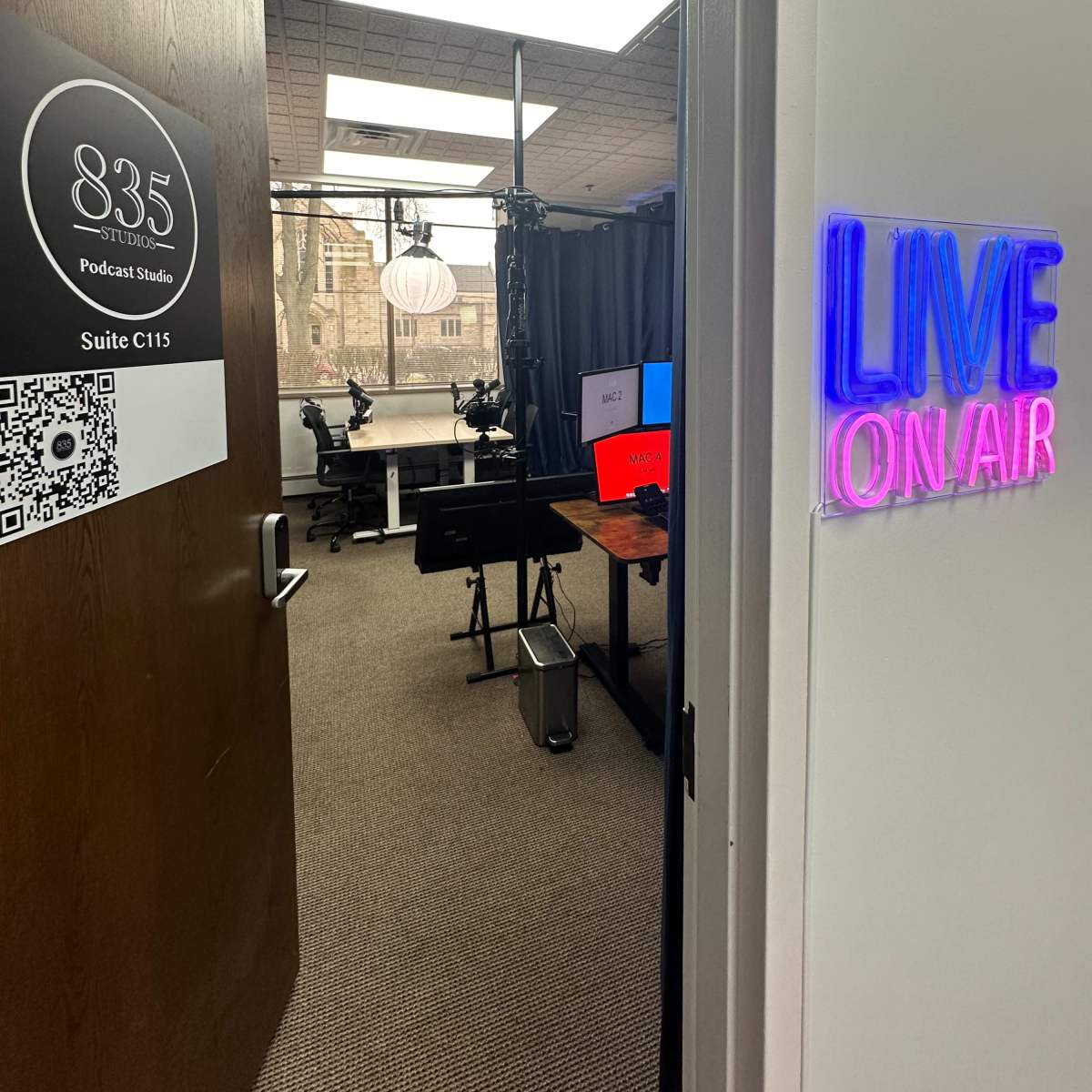 The entrance to a podcast studio with a sign indicating "835 Podcast Studio" and a glowing "LIVE ON AIR" sign alongside the door.