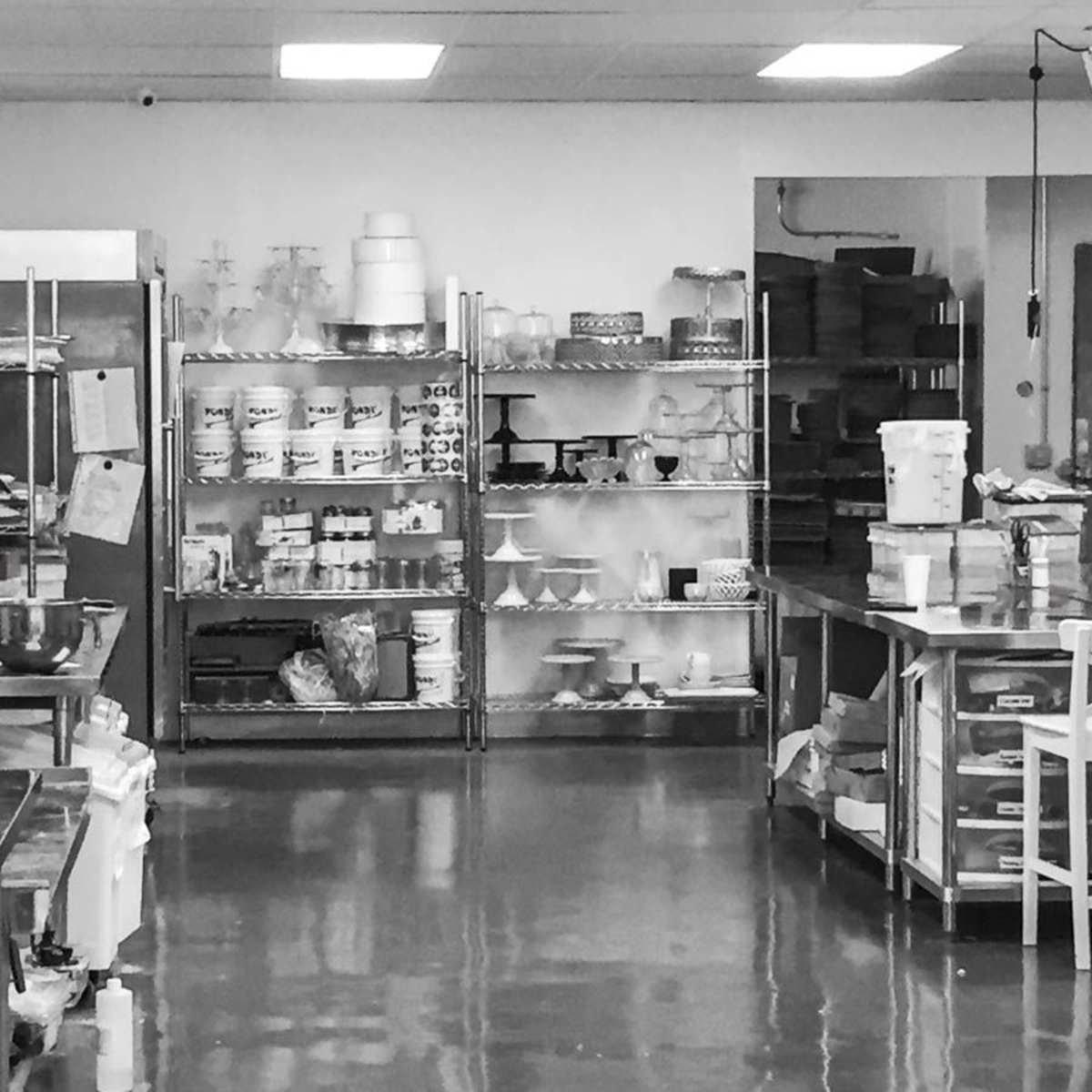 A baking kitchen with metal shelving units filled with various baking supplies and equipment.