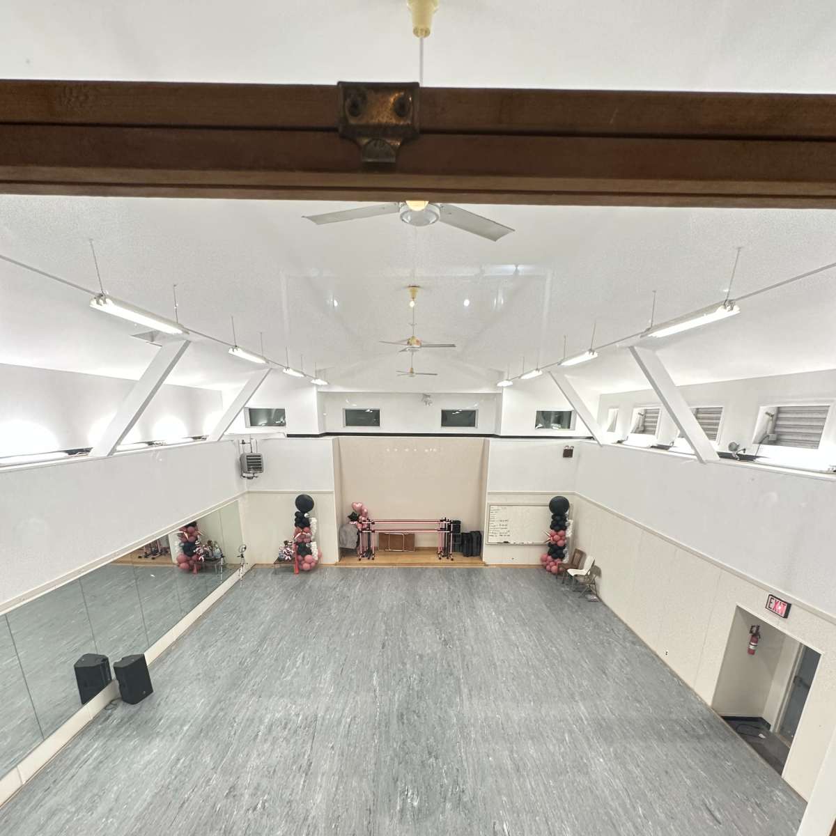 A spacious dance studio with mirrored walls, a smooth floor, and a few benches along one side.