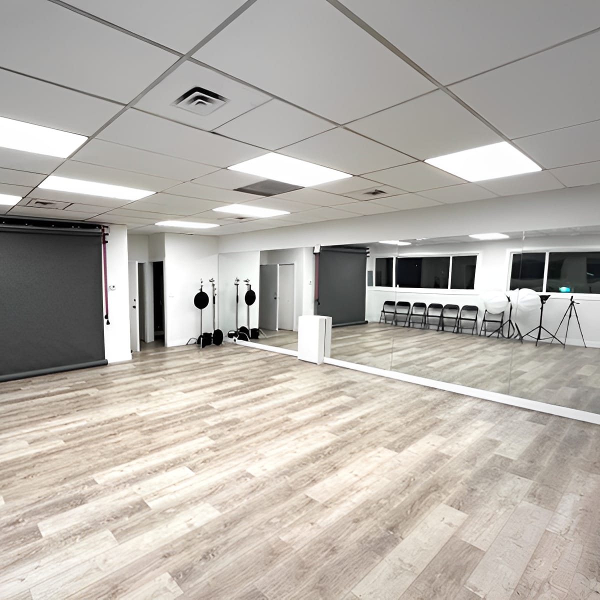 A spacious, well-lit studio with a black backdrop, mirrors, and photography equipment arranged neatly.
