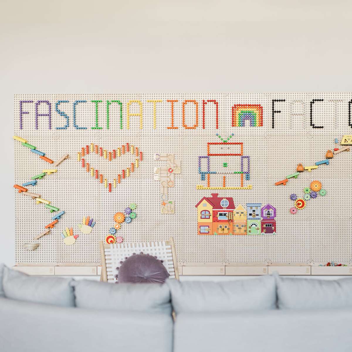 A colorful wall display features various toys and decorations arranged to form the words "FASCINATION" and "FCOY," alongside shapes like hearts and a robot.
